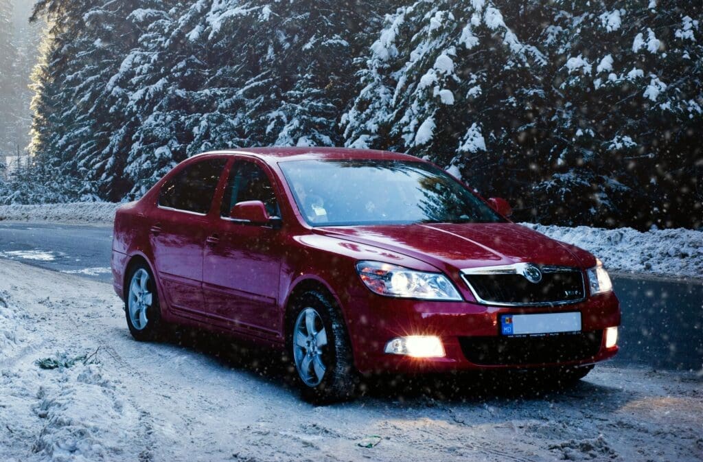 Red car parked in snowy landscape.